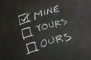 The words "mine," "yours," and "ours," written on a chalkboard with a check mark next to "mine." 