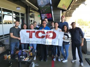 TCGers pose for a picture with the TCG banner at Top Golf.